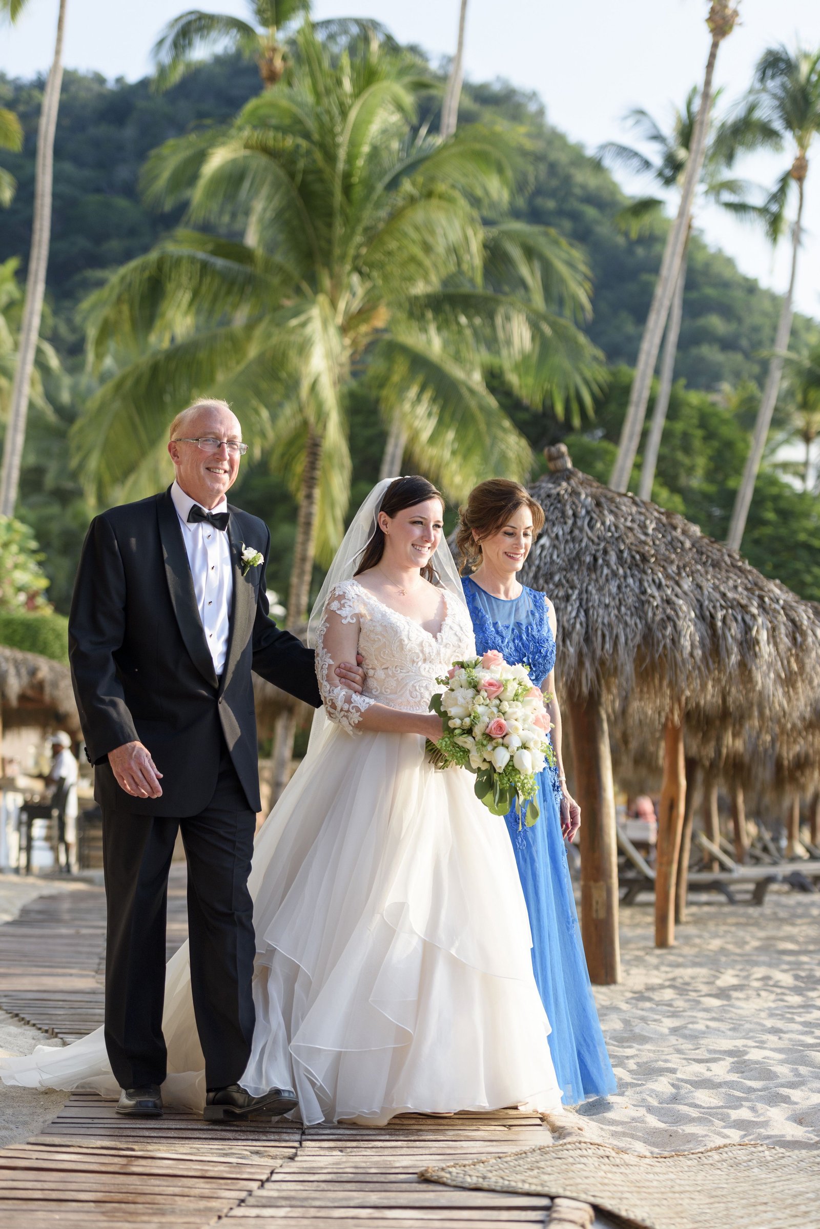 Bride walking down to alter with parents at Hyatt Ziva Puerto Vallarta