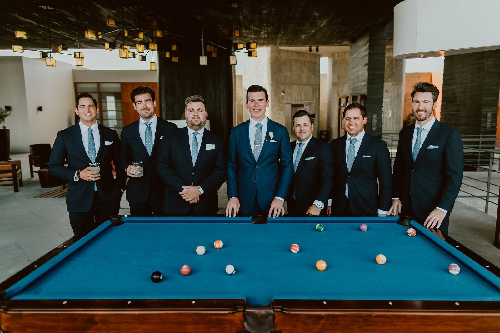 Groom and Groomsmen posing by the Pool Table at the Lobby bar at The Cape in Cabo San Lucas, Mexico. Wedding planning and design by Cabo Wedding Services