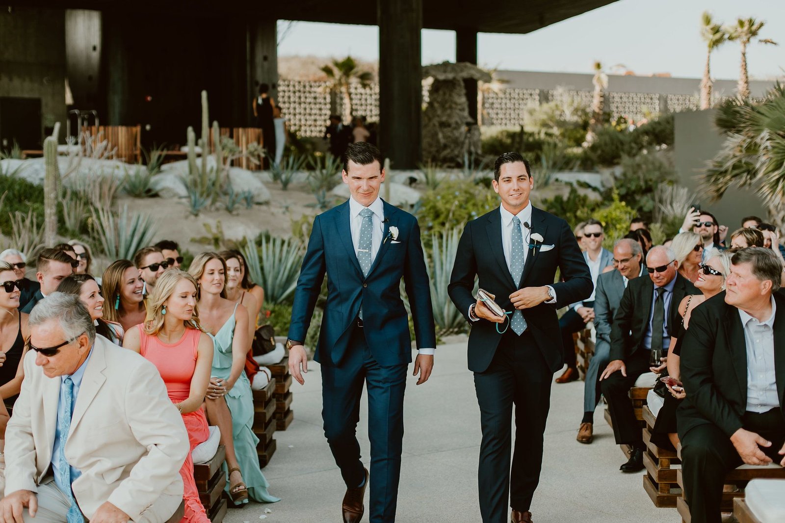 Groom walking down with the officiant during the Ceremony Processional. This photo was taken by Ana and Jerome at The Cape by Thompson Hotels in Los Cabos, Mexico. Wedding Planning by Cabo Wedding Services