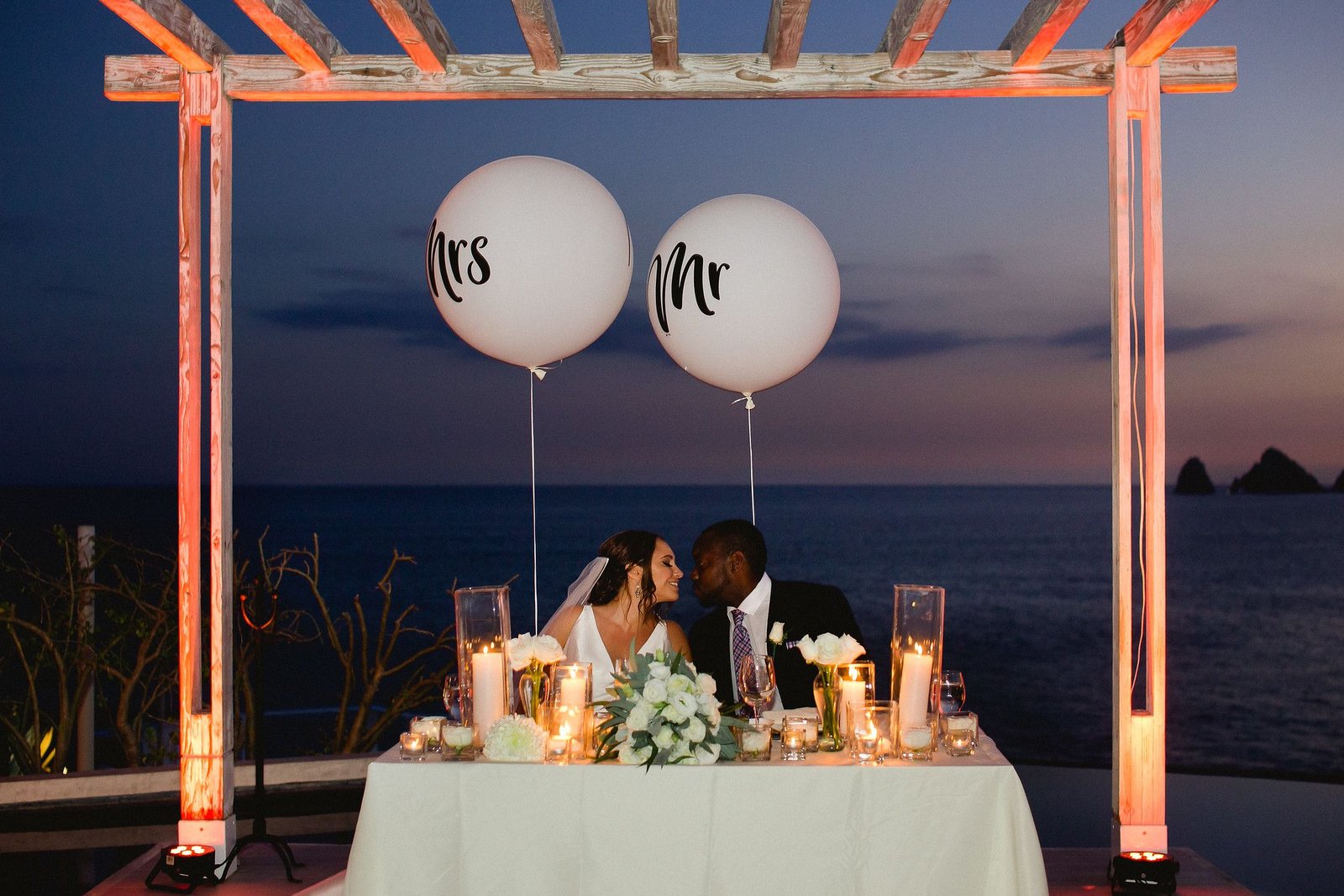 Bride and Groom at their sweetheart table at famous wedding venue in Cabo San Lucas, Mexico. Wedding planning and design by Cabo Wedding Services
