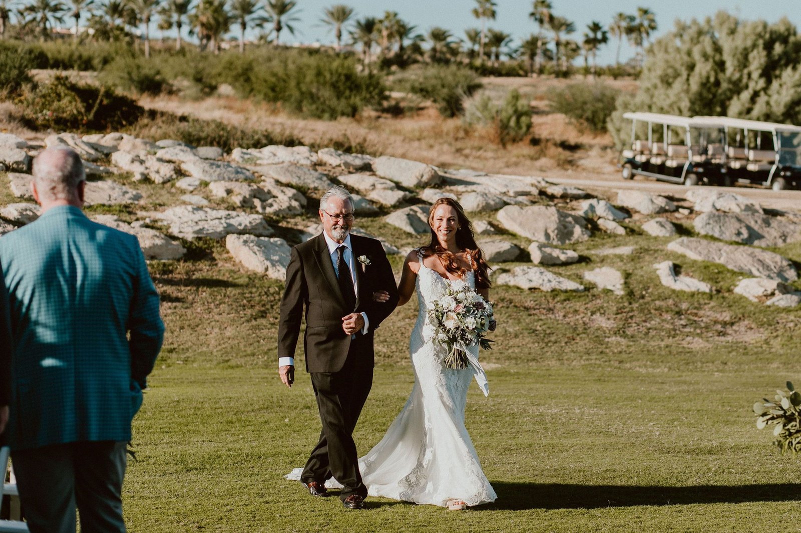 Bride with her dad walking down the Ceremony Aisle at Cabo del Sol Gold Club House. Her Wedding was in Cabo San Lucas, Mexico. Destination Wedding Planning by Cabo Wedding Services.