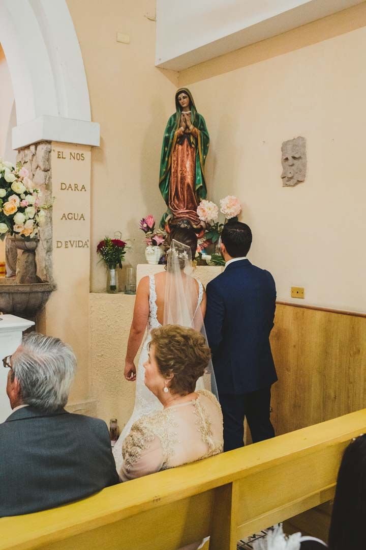 Bride and Groom in front of the Virgin Mary at their Wedding that took place in the Evangelista church in Cabo San Lucas Mexico. One of the oldest churches of the Region, it has seen many marriages throughout the years