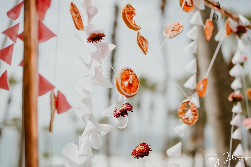 Haldi Backdrop designed by Cabo Wedding Services. It was dried oranges, flowers and beautiful garlands. Haldi ceremony took place at the Hilton Los Cabos, and the wedding planning was done by Cabo Wedding Services.