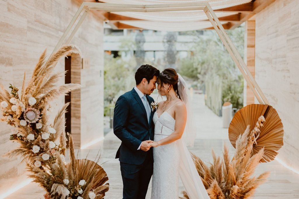 Bride and Groom doing a little photo session around Wedding Venue Solaz in Los Cabos Mexico. They stood in front of what was their ceremony alter that had dried out palm tree's, Pampas grass and beautiful proteas.